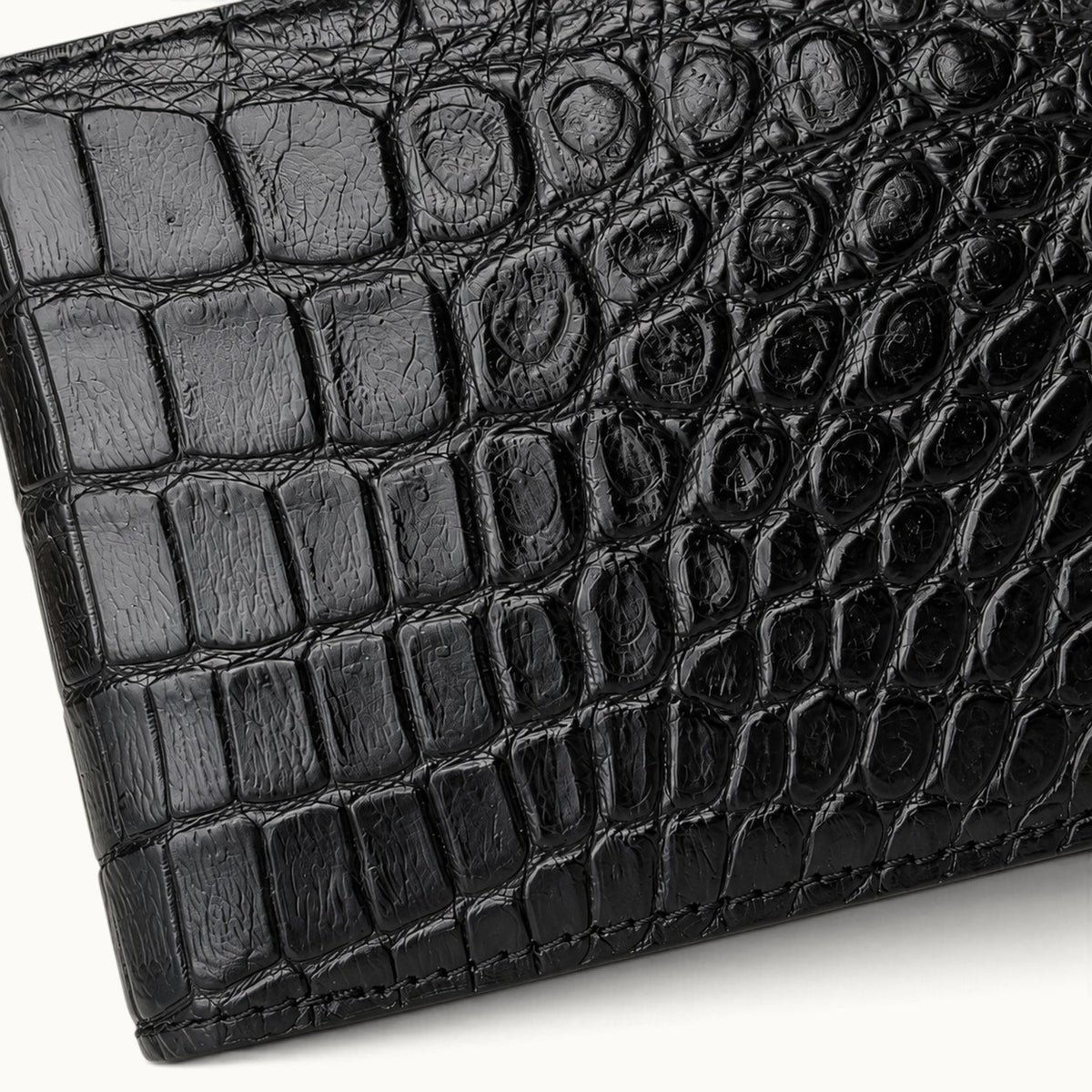 Close-up of The Ashford premium black crocodile bifold wallet, highlighting the genuine Siamese crocodile scale texture, fine stitching, and handcrafted leather finish.