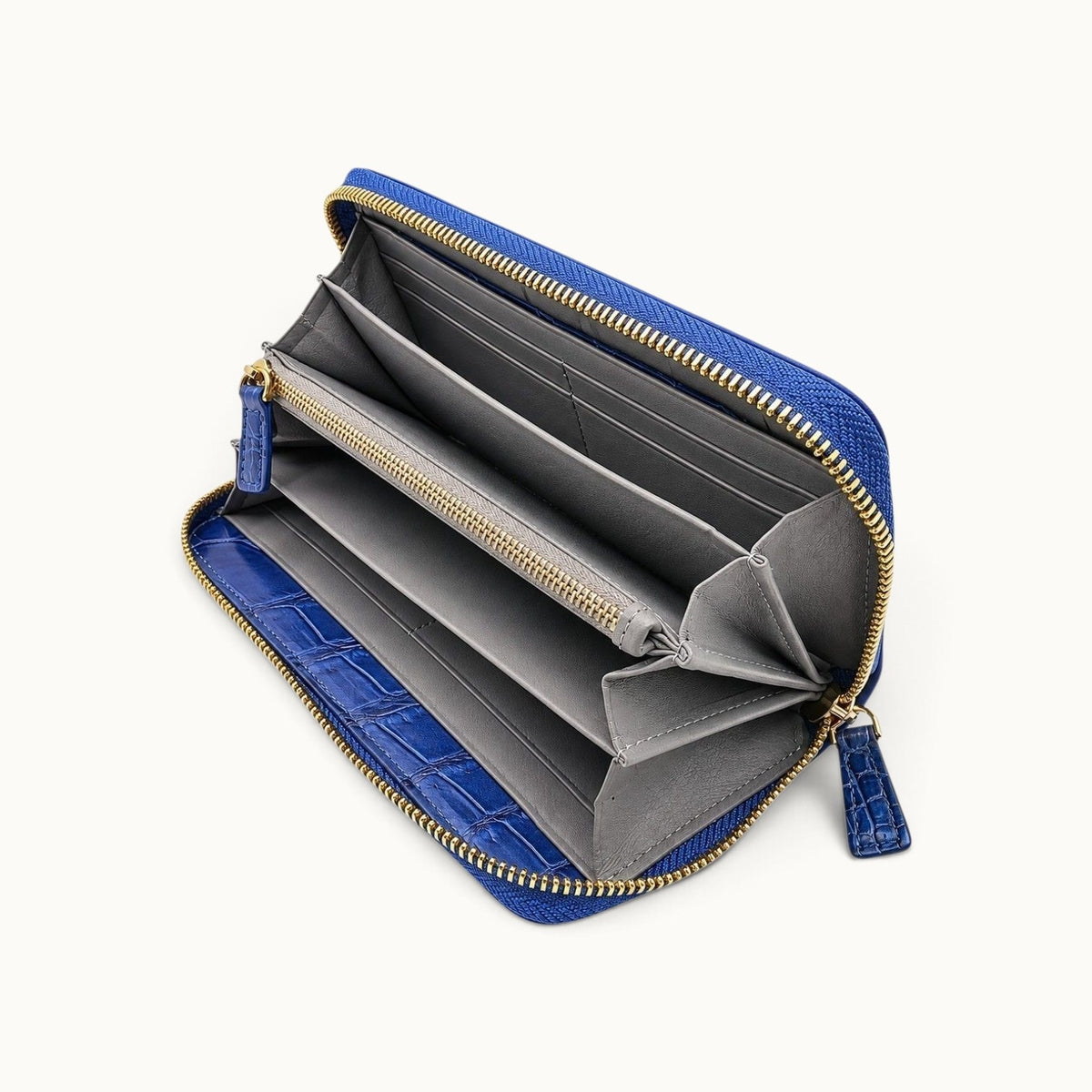 Angled interior view of the Belvedere Siamese crocodile zip-around wallet in Royal Blue showing gray lambskin lining, card slots, compartments, and gold-tone zipper hardware