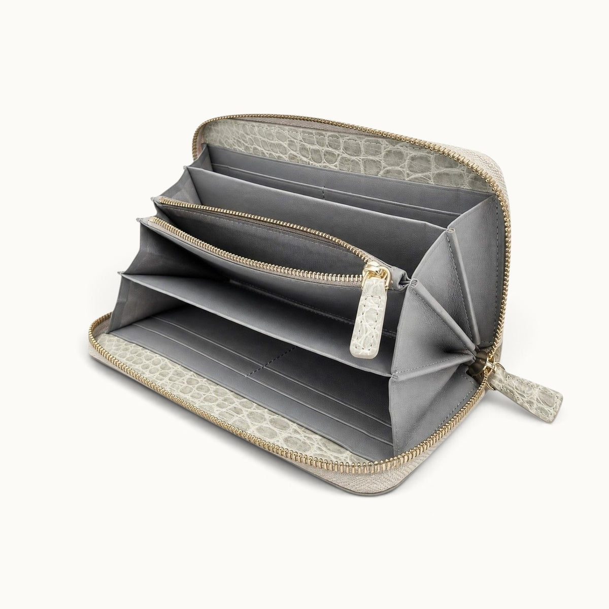 Angled interior view of the Belvedere Siamese crocodile zip-around wallet in Stone Gray with gray lambskin lining, card slots, divided compartments, and central zip pocket