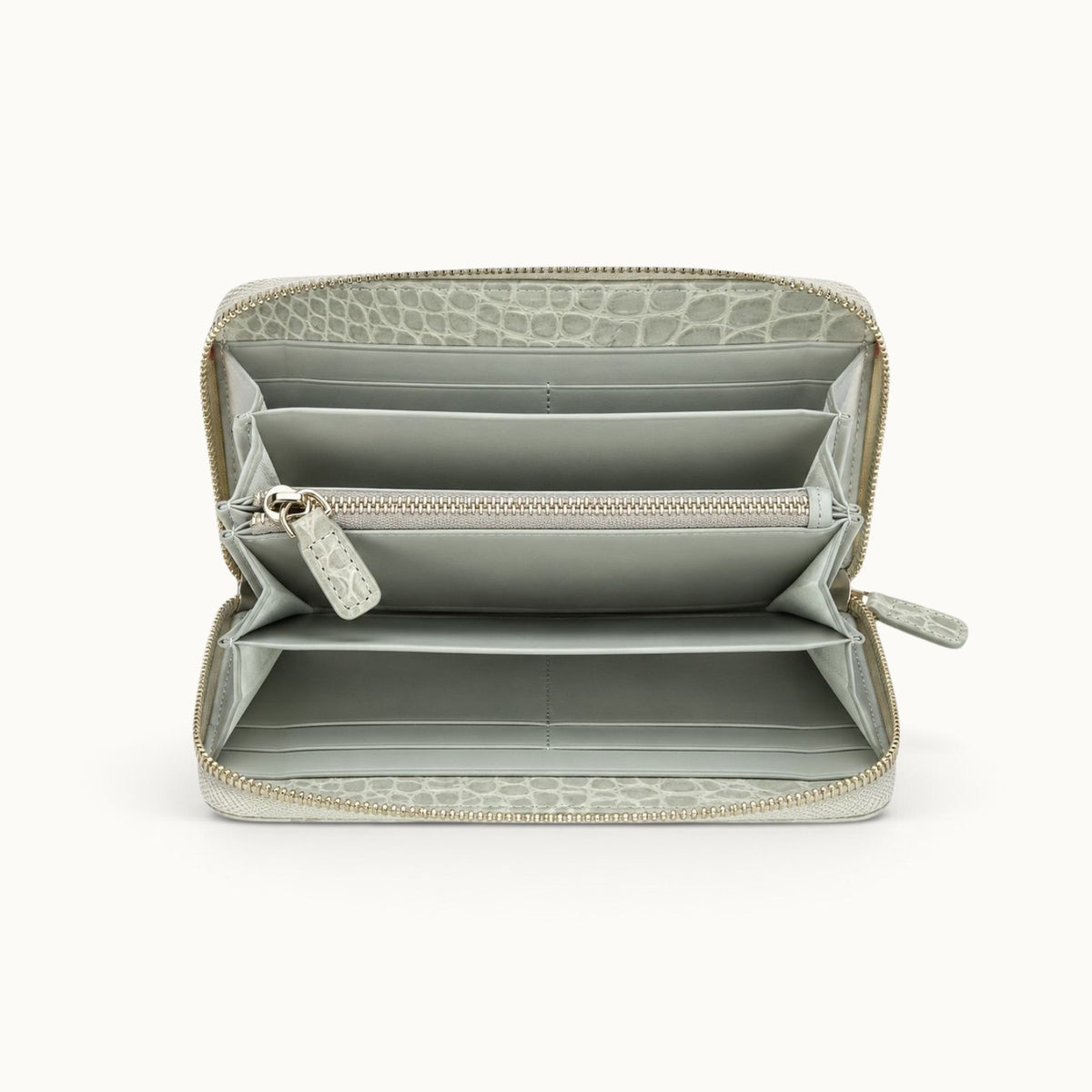 Front interior view of the Belvedere Siamese crocodile zip-around wallet in Stone Gray showing gray lambskin lining, card slots, spacious compartments, and central zip pocket