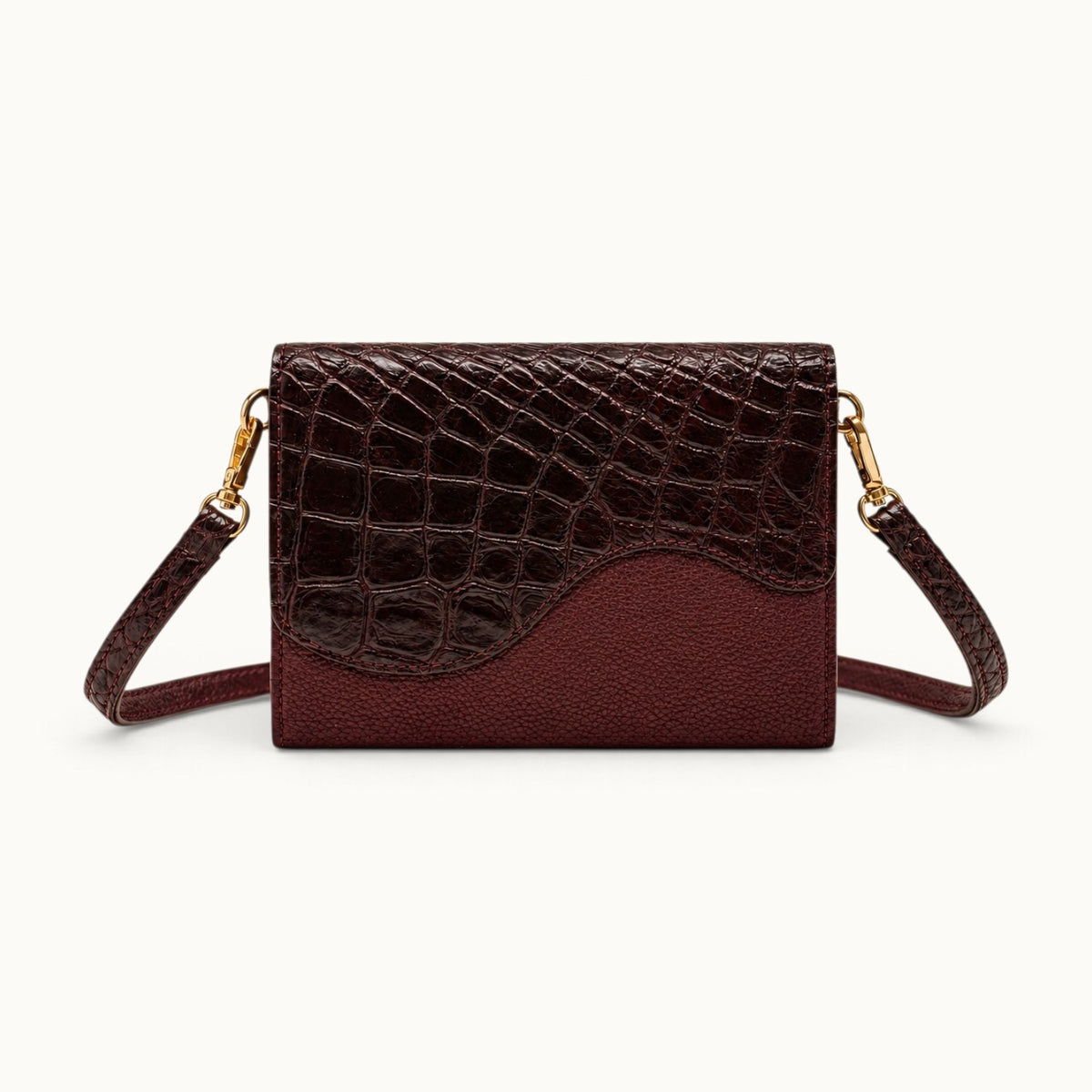 The Berkeley Crocodile Convertible Wallet in Bordeaux with a removable crocodile leather shoulder strap and gold-tone hardware.