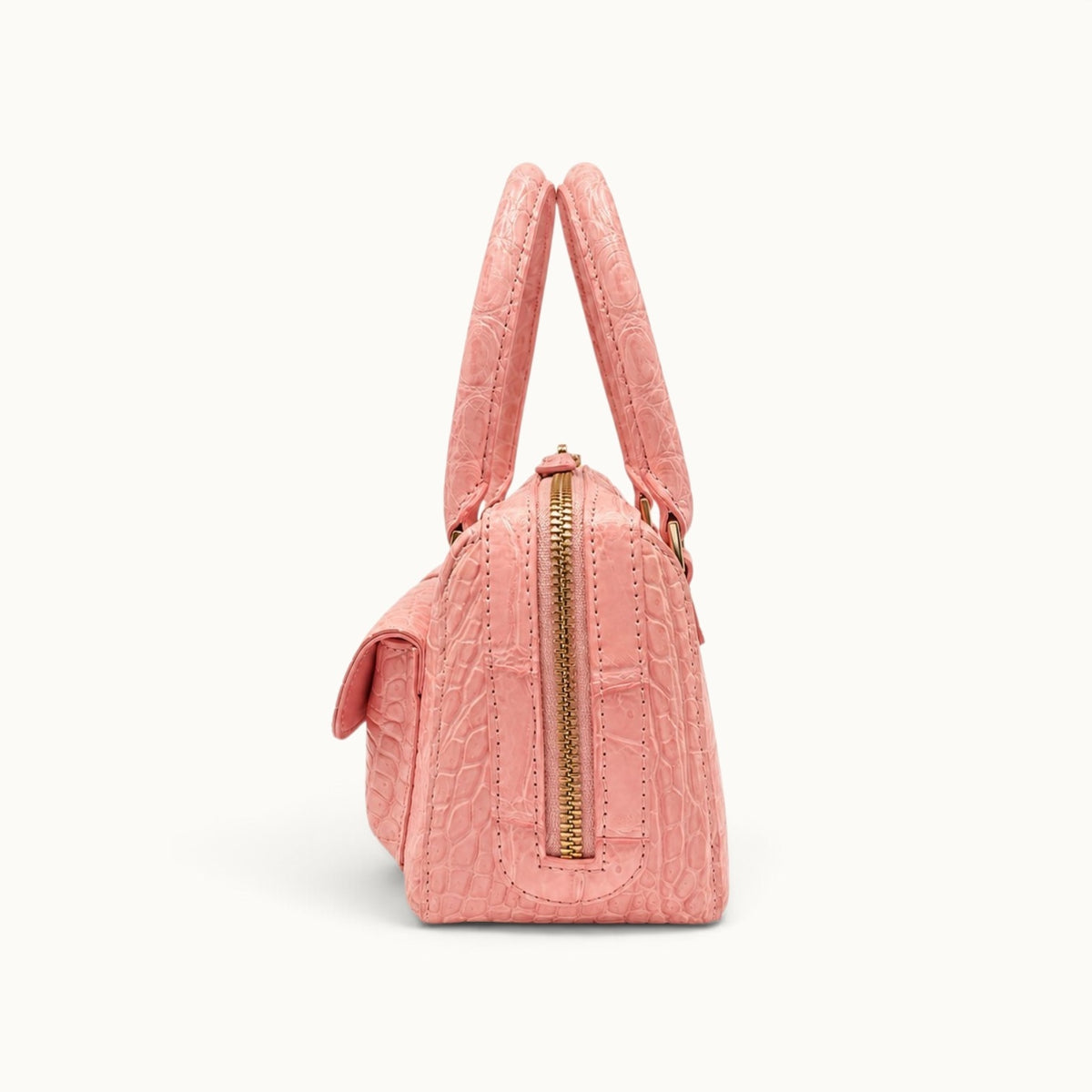 Side view of The Fairmont blush pink crocodile handbag with structured silhouette, zip-top closure, and gold-tone hardware.