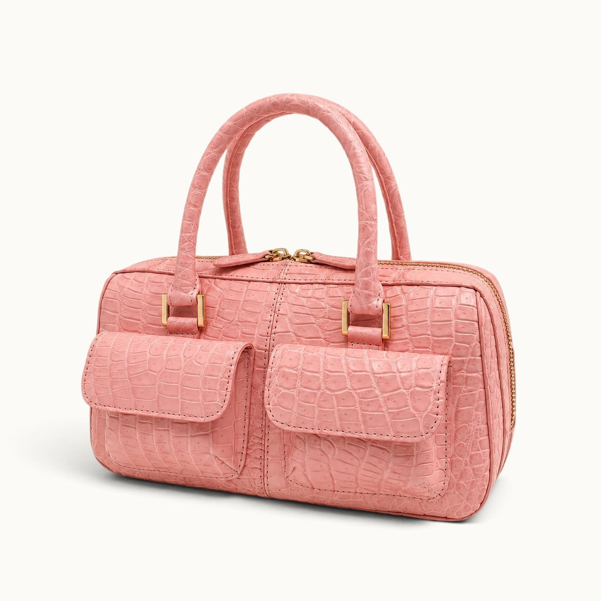 Angled view of The Fairmont Crocodile Handbag in blush pink showing the front pockets, structured body, and luxurious exotic leather finish.