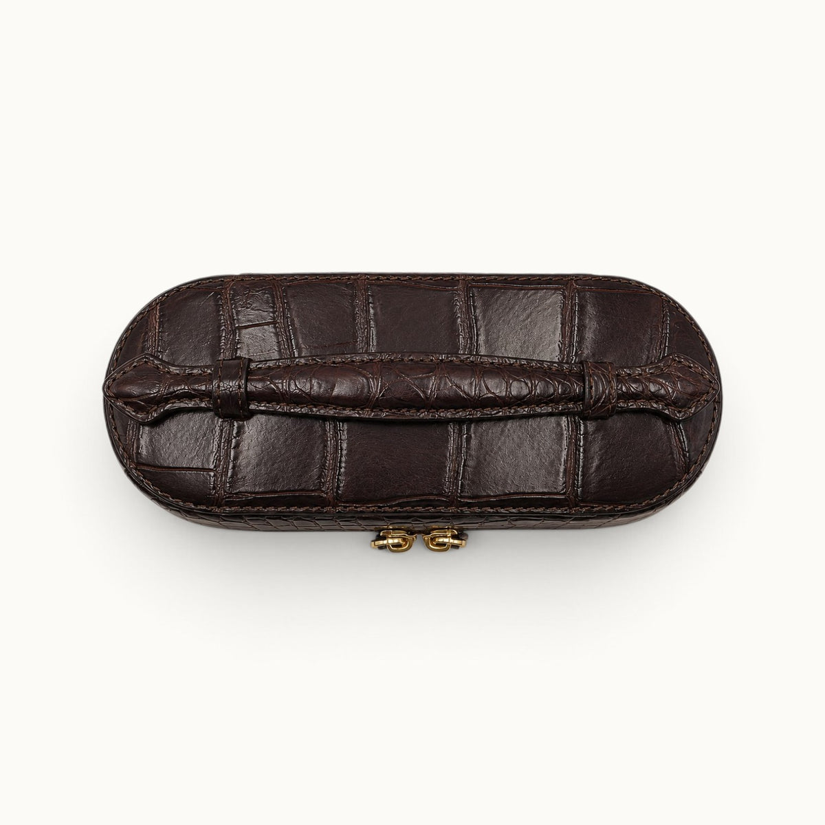 Top view of The Clarendon Bordeaux crocodile vanity case highlighting the sculpted crocodile handle and hand-painted edges.