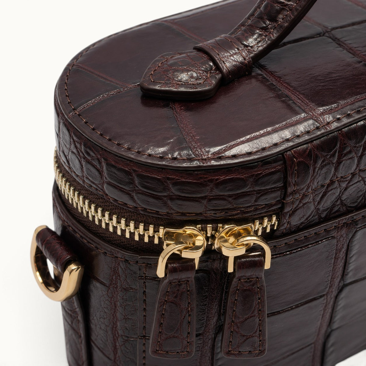 Close-up of genuine Bordeaux crocodile skin displaying natural scale texture, precision stitching and luxury leather craftsmanship.