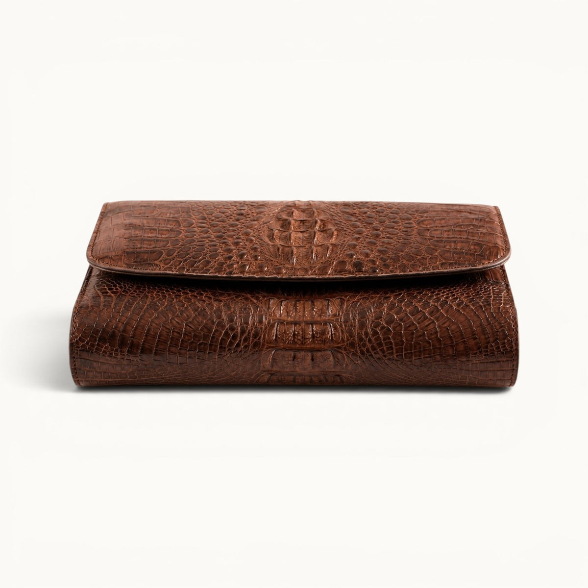 Bottom view of The Cavendish genuine caiman crocodile leather clutch bag in rich brown, showing its rounded base, natural scale pattern, and structured construction.