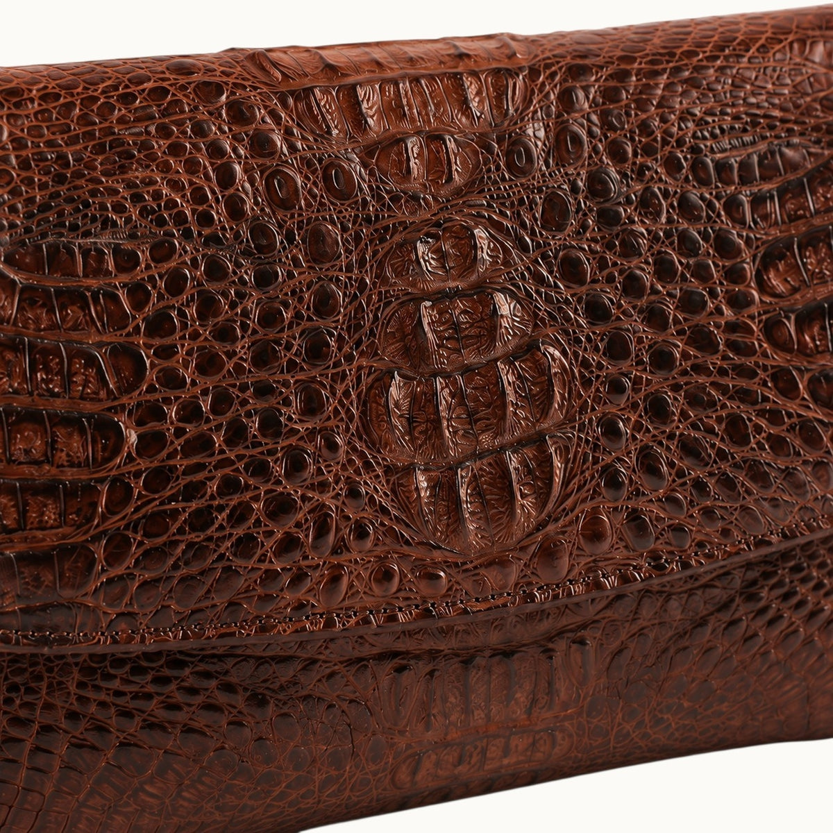 Close-up of The Cavendish genuine caiman leather shoulder clutch in rich brown, highlighting the distinctive natural scale pattern, fine stitching, and glossy exotic leather texture.