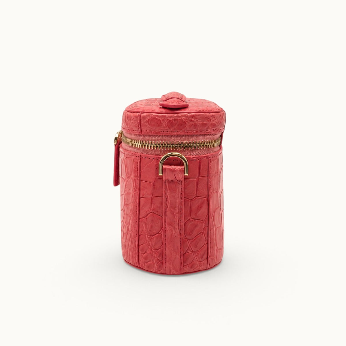 Side profile of a Coral Red crocodile crossbody vanity bag showing the strap attachment and compact structured silhouette.
