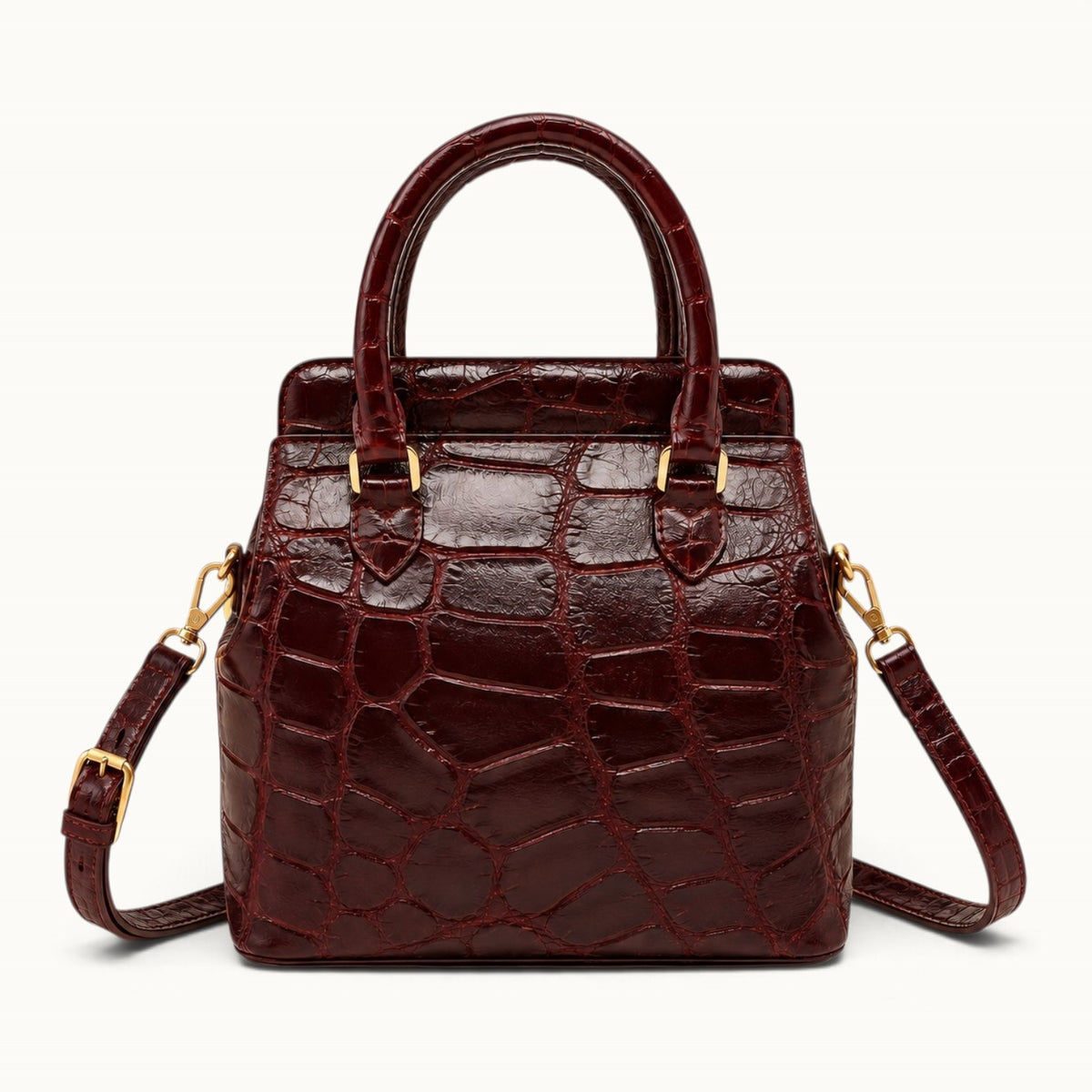 The Ellery Crocodile Handbag in Bordeaux with detachable shoulder strap connected to gold-tone side D-rings.