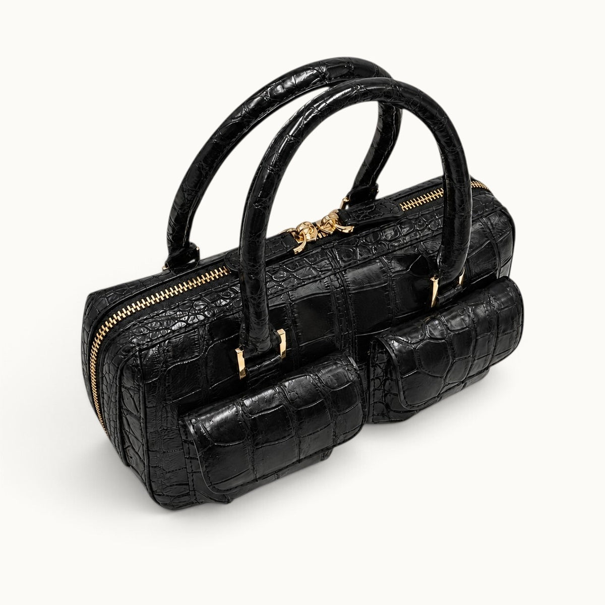 Elevated three-quarter view of the Fairmont Classic Black Siamese crocodile handbag highlighting the front pockets, handles, and gold-tone zipper.