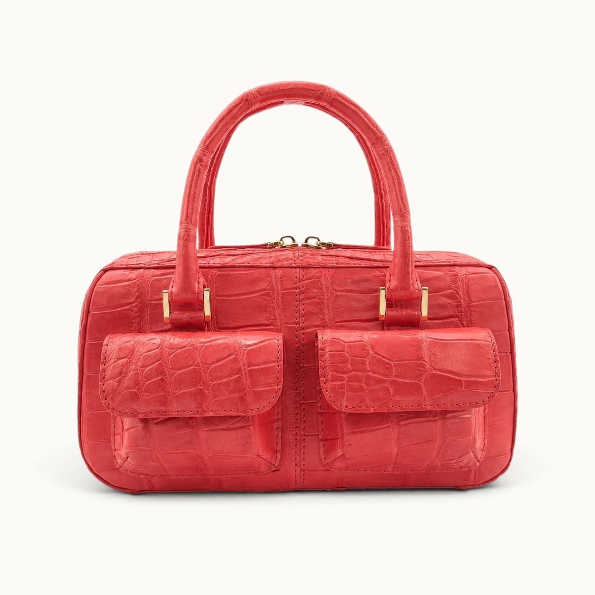 The Fairmont Crocodile Handbag in coral red, front view with dual flap pockets, top handles and gold-tone hardware.