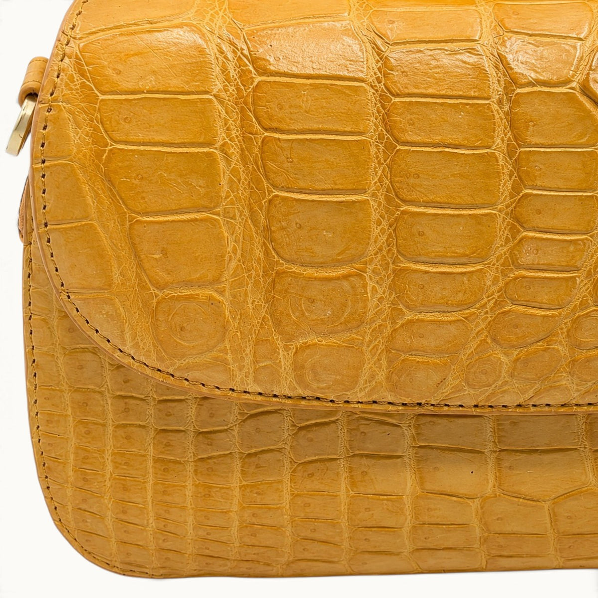 Close-up of the natural Siamese crocodile leather scale pattern and stitching on the Grosvenor crossbody bag in Golden Mustard.