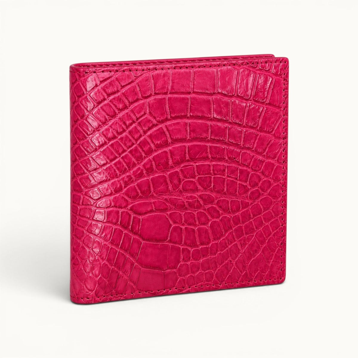 Herrington Bright Pink genuine Siamese crocodile trifold wallet shown from an angled front view, highlighting the glossy scale texture and slim folded profile.