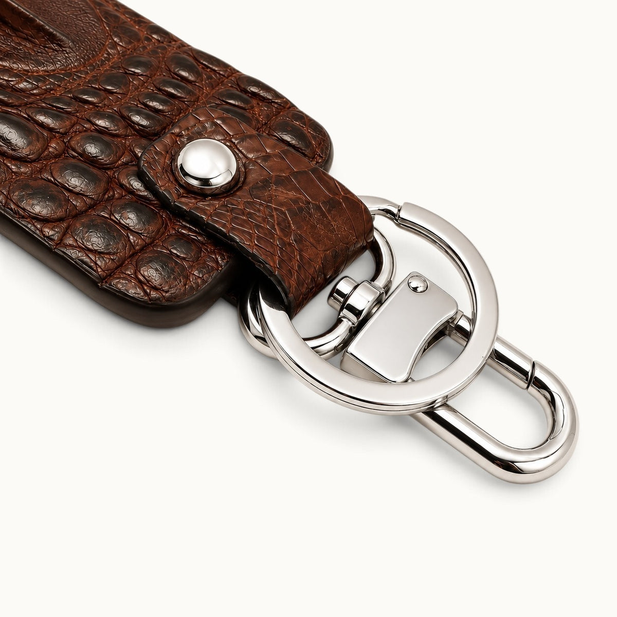 Close-up of the Kensington brown alligator leather key fob showing the polished silver swivel clasp, large key ring, snap closure, and natural scale texture.