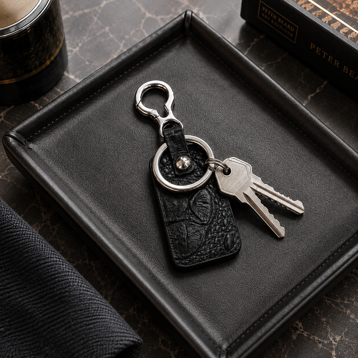 Kensington small black genuine alligator leather key fob with two silver keys on a luxury black leather valet tray.