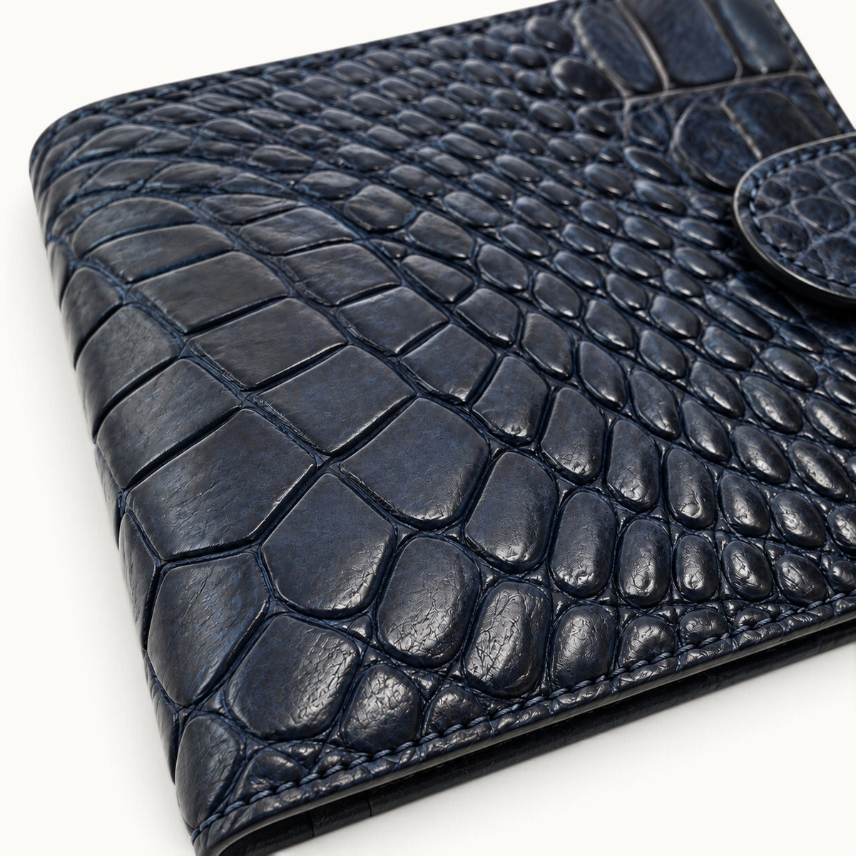 Close-up of the deep navy Langham crocodile wallet showing the natural scale pattern and leather texture