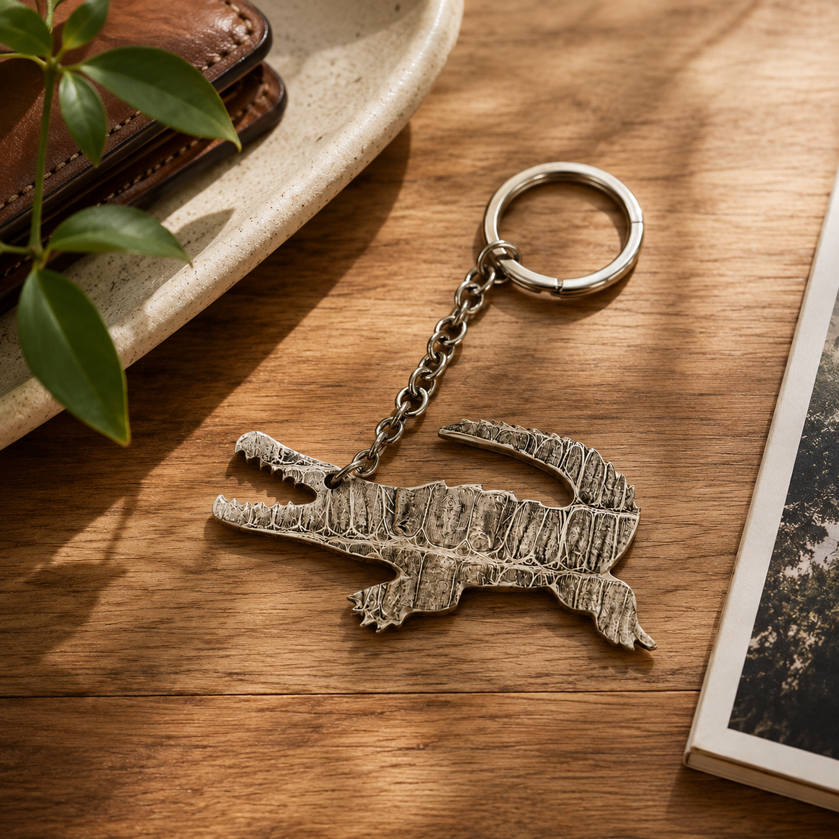 Stone ivory Siamese crocodile leather key charm styled on a wooden surface beside natural accessories