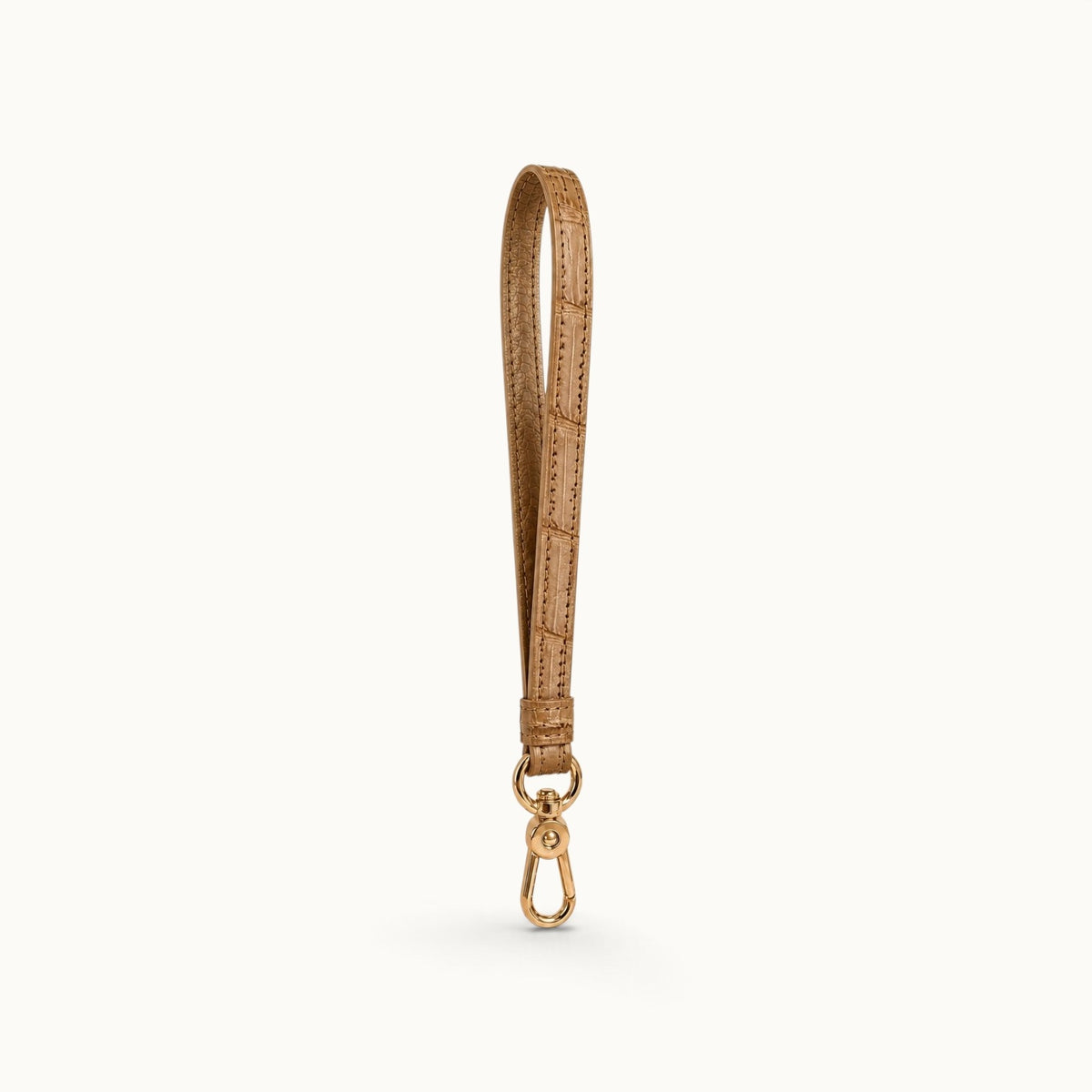 Angled view of the Sand Beige Stanhope crocodile wrist strap showing the crocodile texture, cow leather interior, and polished gold-tone clasp.