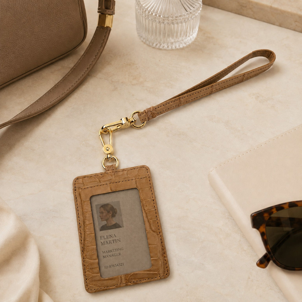Sand Beige Stanhope crocodile wrist strap with gold-tone clasp attached to a matching crocodile ID holder in a refined neutral setting.