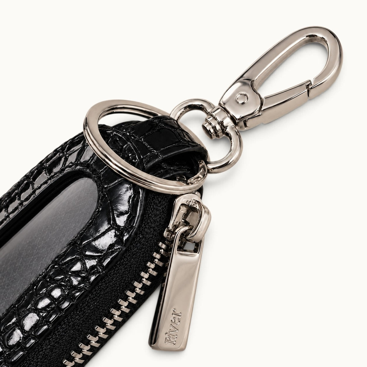 Close-up of the black Siamensis crocodile leather car key case showing the polished brass clasp, key ring, YKK zipper pull, and clear front window.