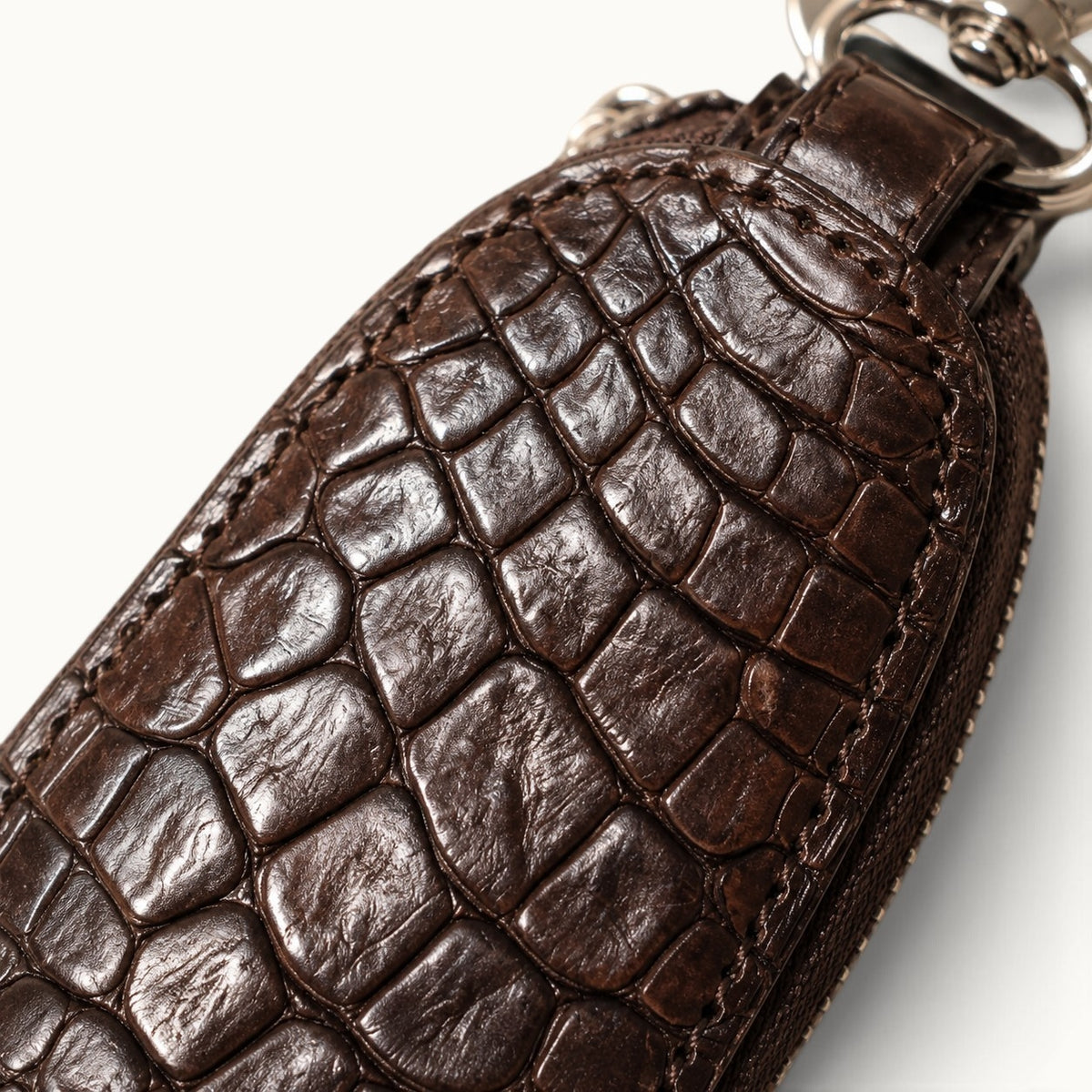 Close-up texture of the brown Siamensis crocodile leather car key case, showing the natural scale pattern and rich hand-finished surface.