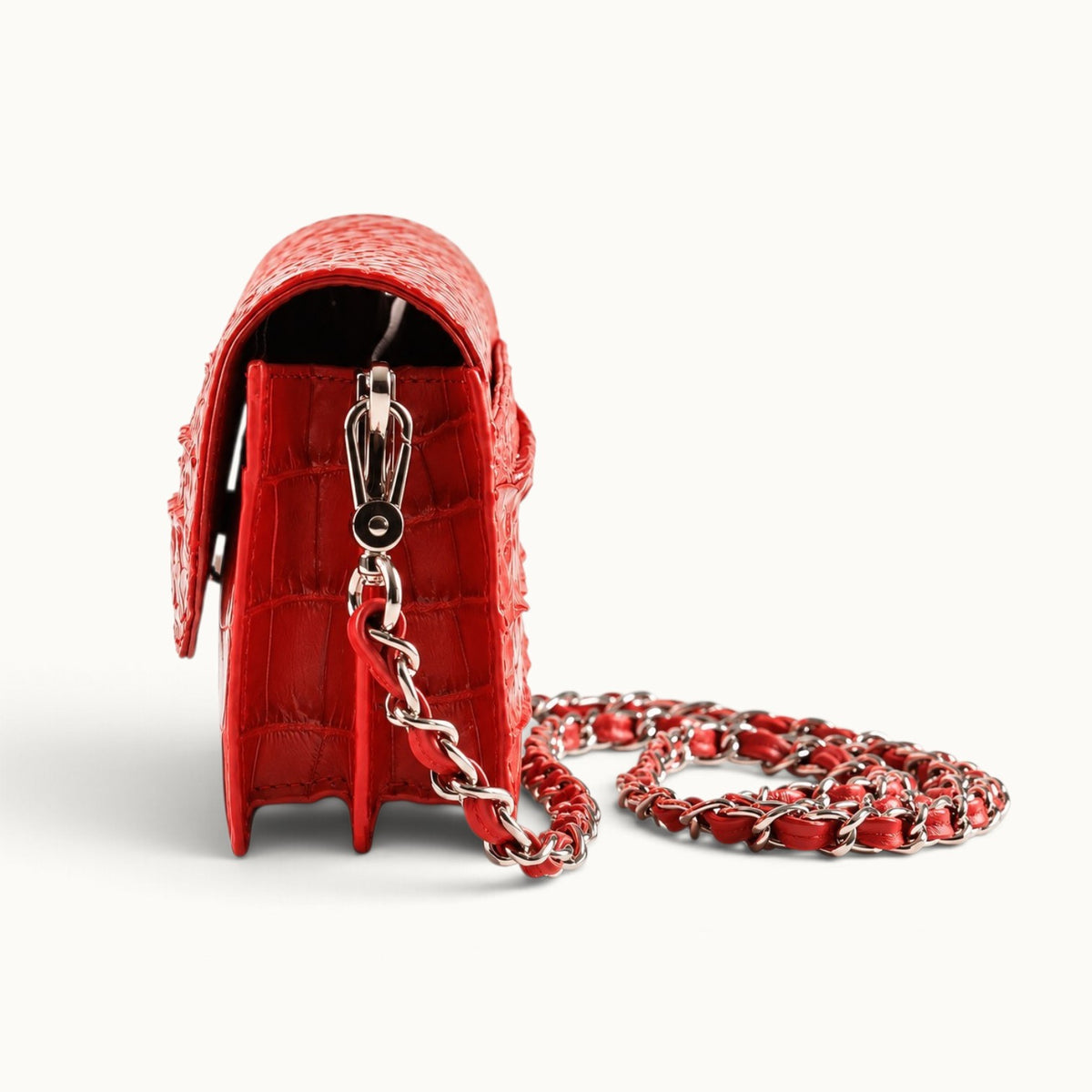Side view of The Chelsea red crocodile leather shoulder bag showing its gusseted compartments and silver-tone strap clasp.