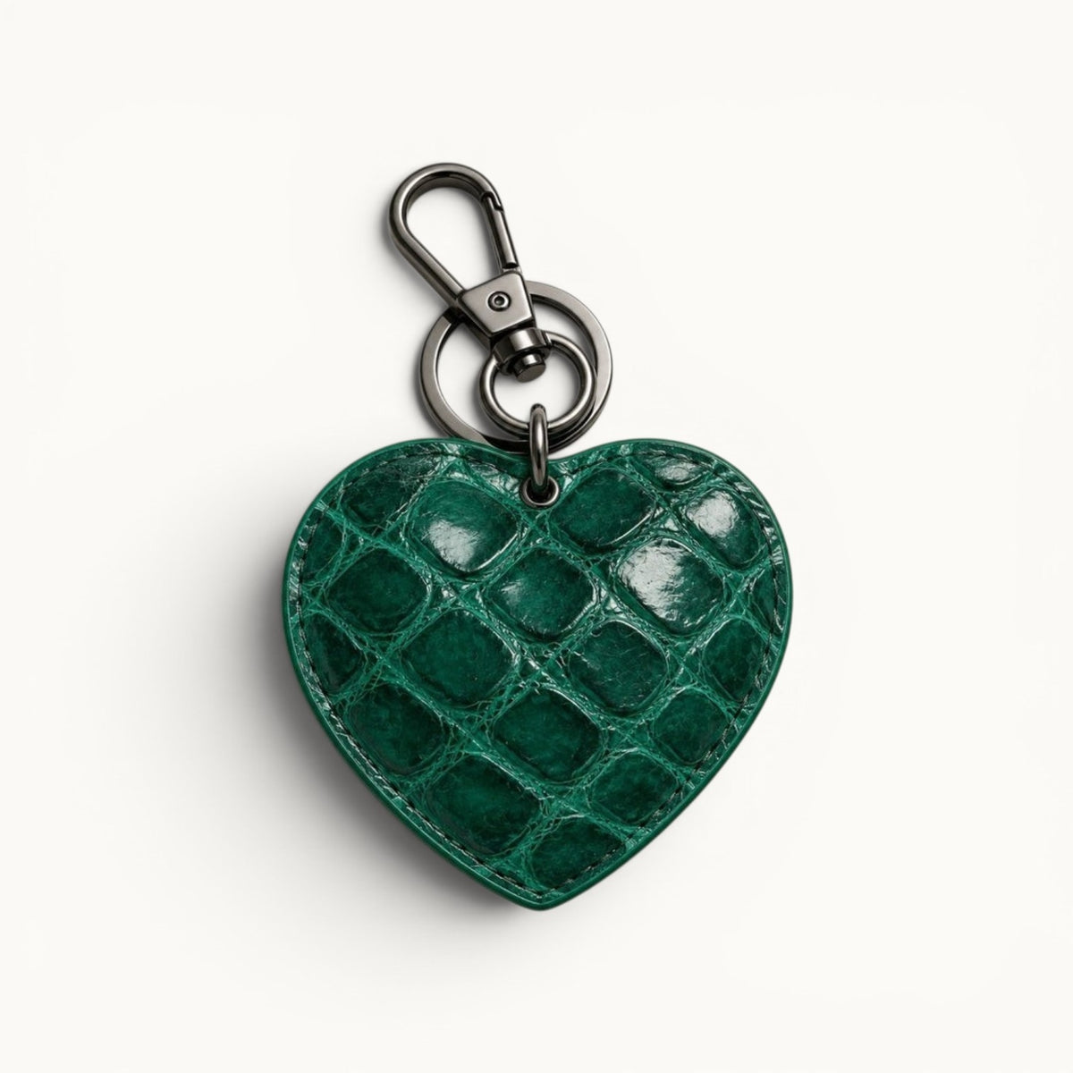 The Heart Key Charm in emerald green Siamese crocodile leather with glossy natural scales, stitched edges, and polished silver-tone clasp hardware.
