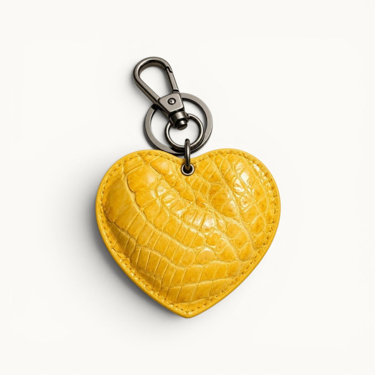 The Heart Key Charm in golden yellow Siamese crocodile leather featuring a natural scale pattern, stitched heart shape, and polished silver-tone clasp.