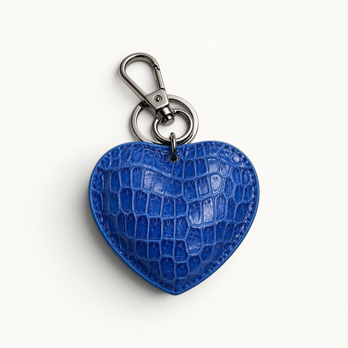 The Heart Key Charm in royal blue Siamese crocodile leather with natural scales, a polished silver-tone clasp, and circular keyring.
