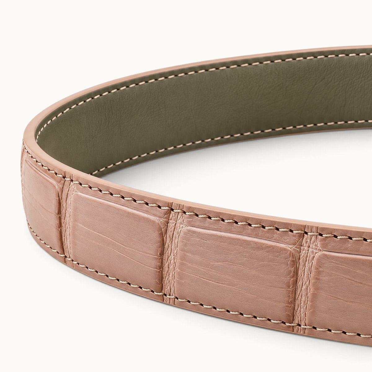Close-up of The Rosalie Crocodile Belt showing blush pink crocodile leather, contrasting olive-gray cow leather backing, and precise edge stitching.