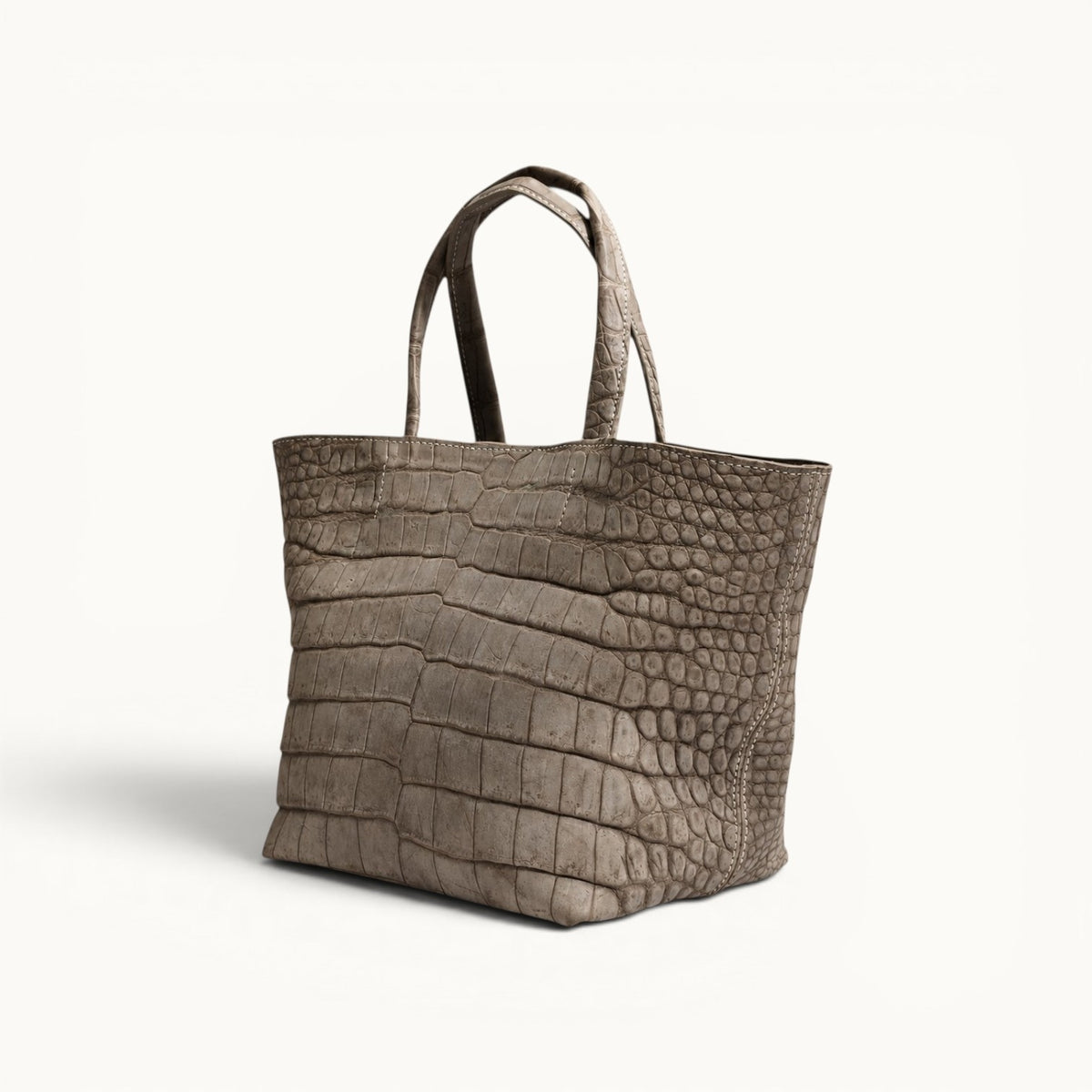 Angled view of The Atelier Tote luxury Porosus crocodile leather tote bag, handcrafted from genuine Porosus crocodile leather with a distinctive natural scale pattern.