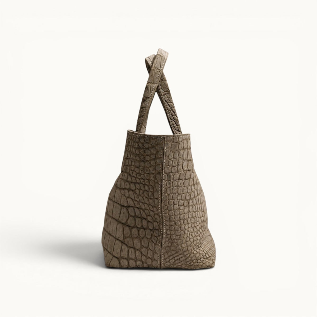 Side view of The Atelier Tote luxury Porosus crocodile leather tote bag, handcrafted from genuine Porosus crocodile leather with a structured silhouette and distinctive natural scale pattern.