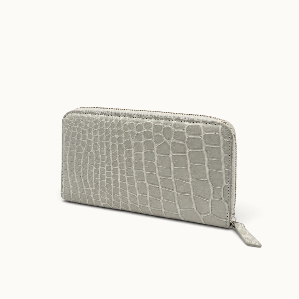 Angled view of the Belvedere Siamese crocodile zip-around wallet in Stone Gray with natural scale pattern and gold-tone hardware