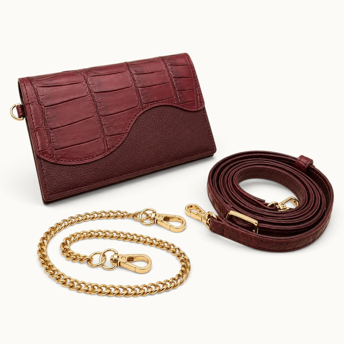 The Berkeley Crocodile Convertible Wallet in Burgundy shown with its removable gold-tone chain and matching adjustable crocodile leather shoulder strap.