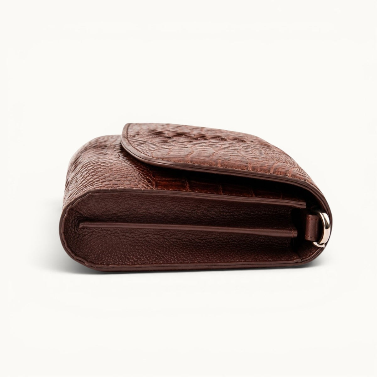 Side profile of The Cavendish genuine caiman leather shoulder clutch bag in rich brown, showing its rounded base, structured gusset, and full-grain leather interior.