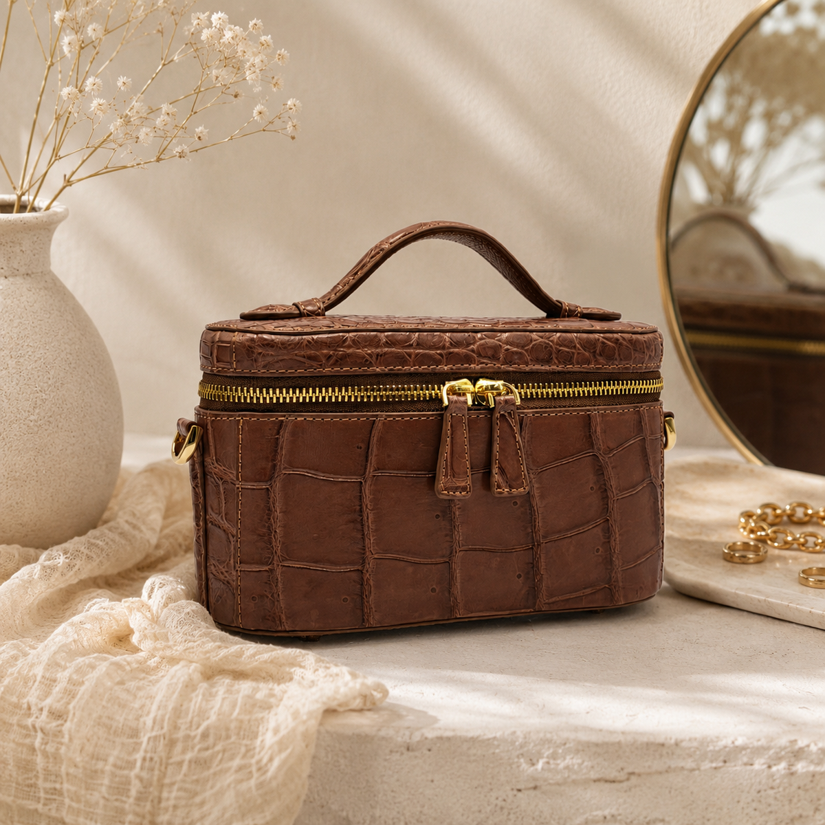 Cocoa Brown Clarendon crocodile mini box bag in a luxury vanity setting, featuring genuine Siamese crocodile leather, a structured top handle silhouette, gold-tone hardware, and an elegant compact designer evening bag look.