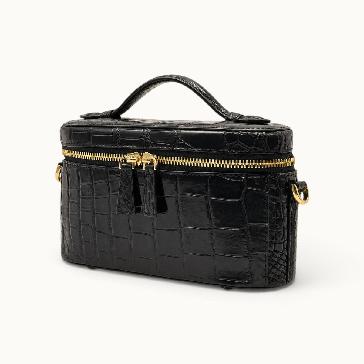 Angle view of a Classic Black luxury crocodile top handle bag with structured mini vanity silhouette and double zipper closure.