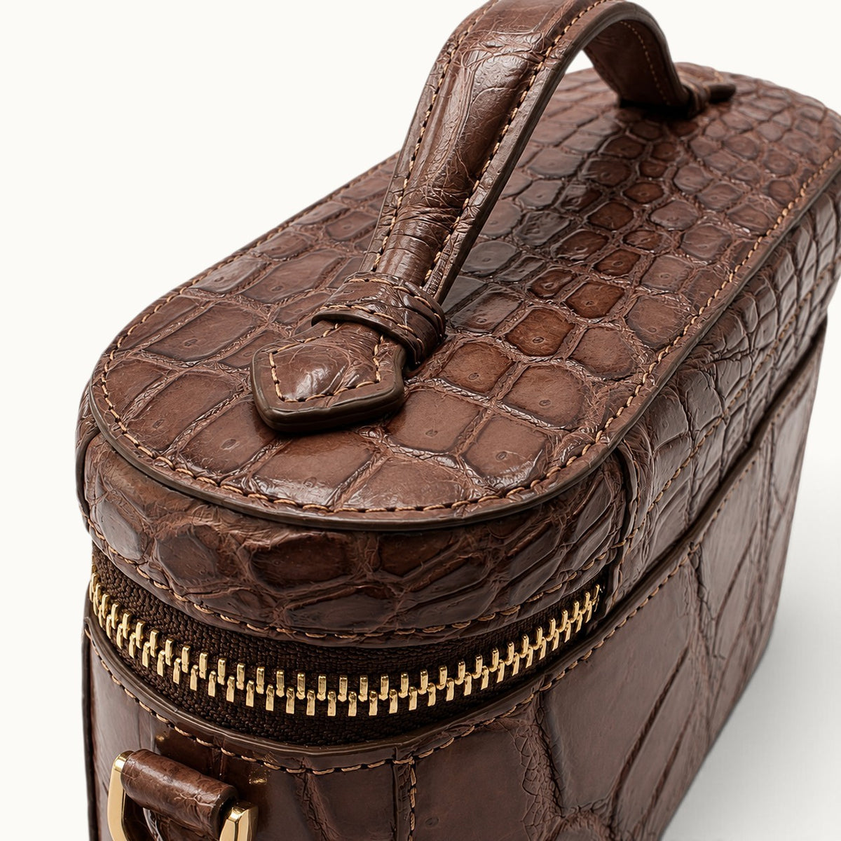 Craftsmanship close-up of Cocoa Brown exotic crocodile leather, hand stitching, piping and premium gold-tone zipper hardware.