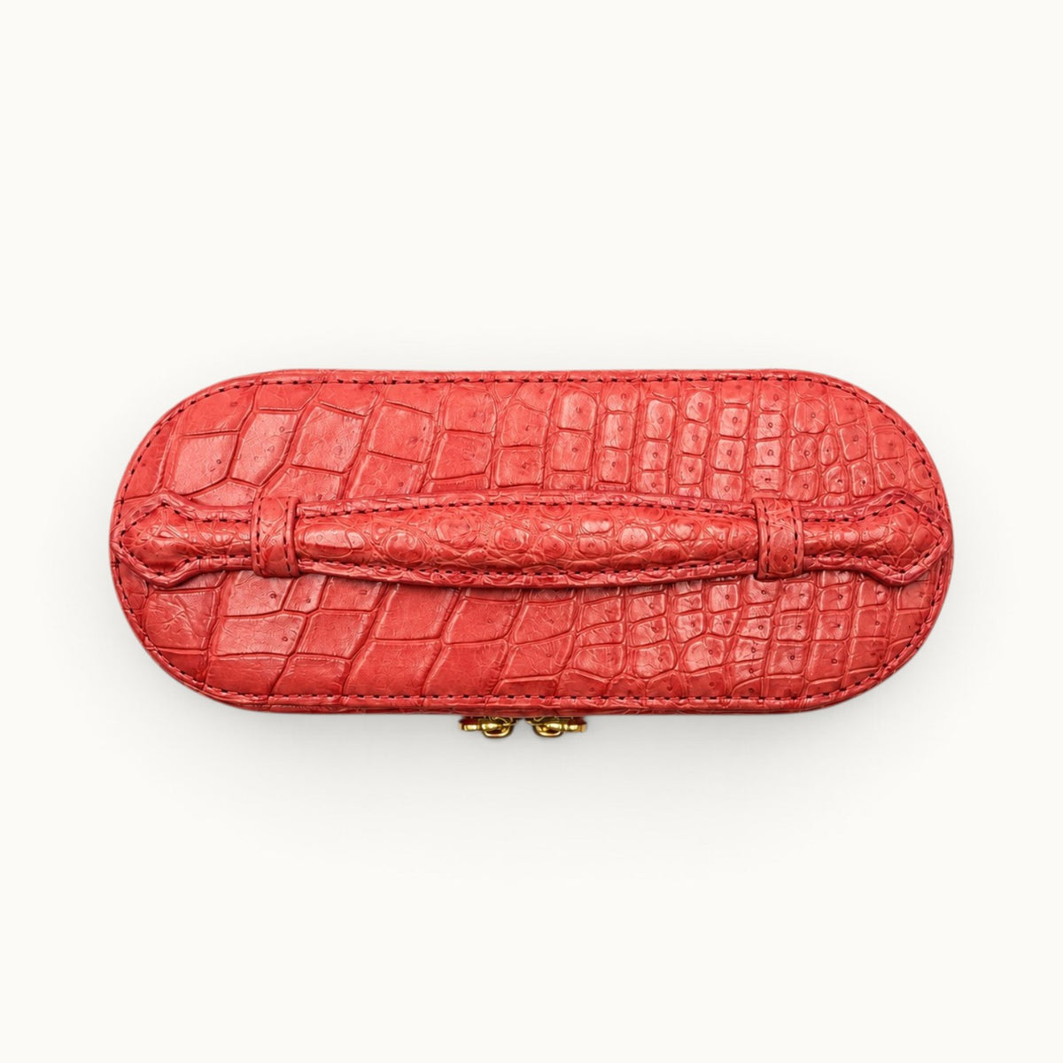 Top view of The Clarendon Coral Red crocodile top handle box bag highlighting the natural scale pattern and hand-finished handle.