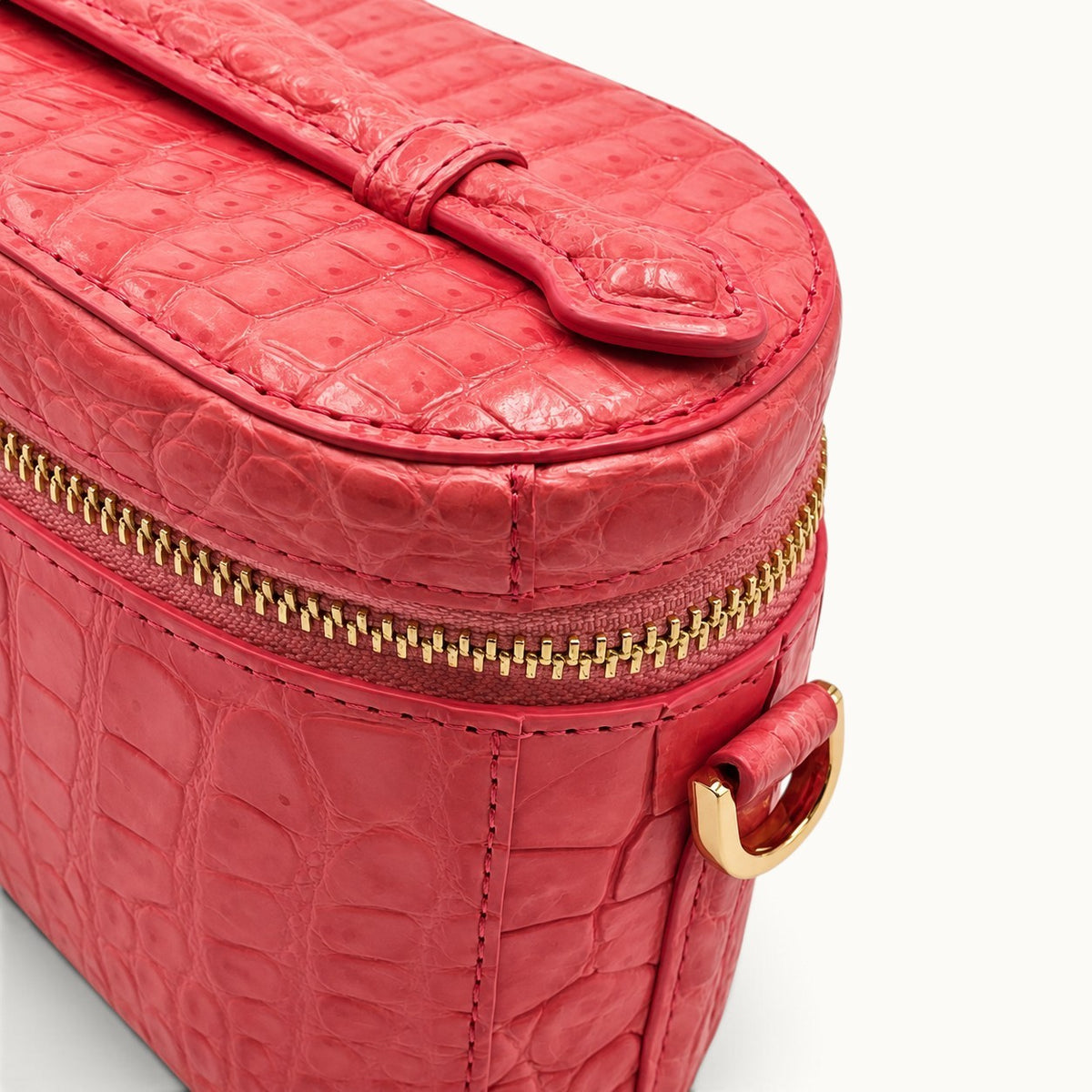Detail close-up of Coral Red exotic crocodile leather with gold-tone YKK zipper, stitching and handcrafted scale texture.