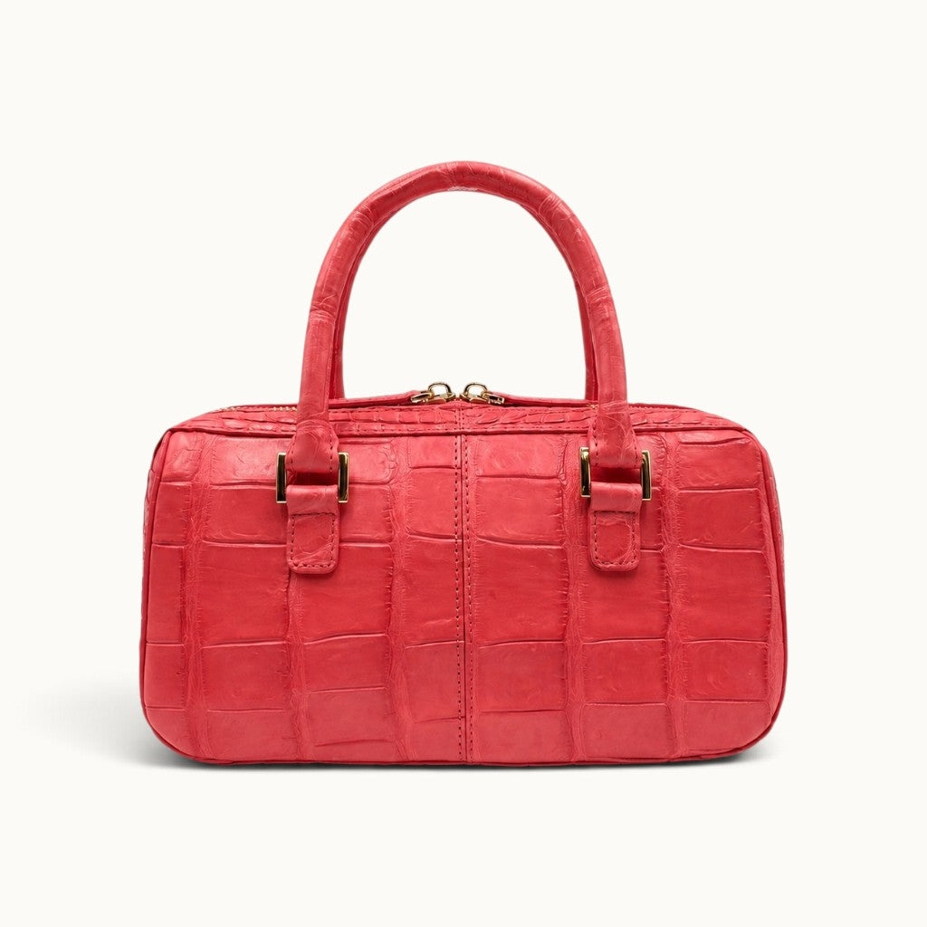 Back view of The Fairmont coral red crocodile handbag showing the natural scale pattern and structured silhouette.