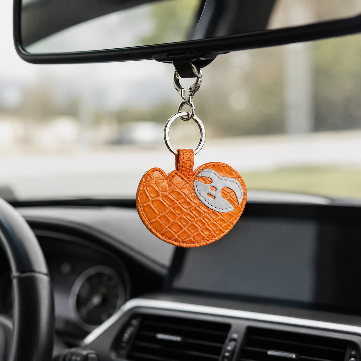 Burnt Orange Crocodile Palette Bag Charm hanging from a car rearview mirror