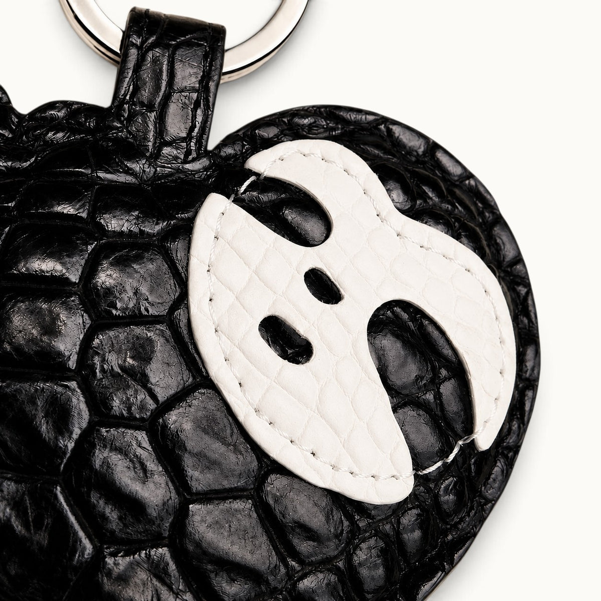Close-up detail of the white leather mask motif on the Jet Black Crocodile Palette Bag Charm