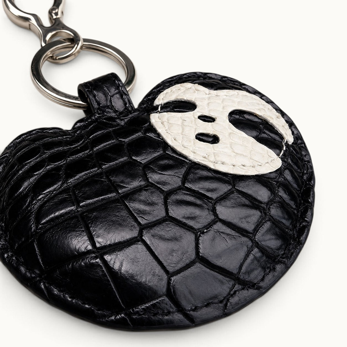 Close-up of Jet Black Crocodile Palette Bag Charm showing glossy crocodile scales, stitching, and white mask detail
