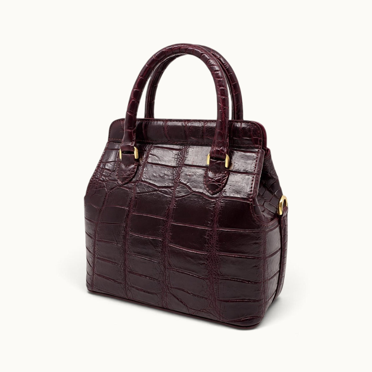 Three-quarter angle of The Ellery Crocodile Handbag in Bordeaux, showing its structured silhouette, side gusset, and gold D-ring.