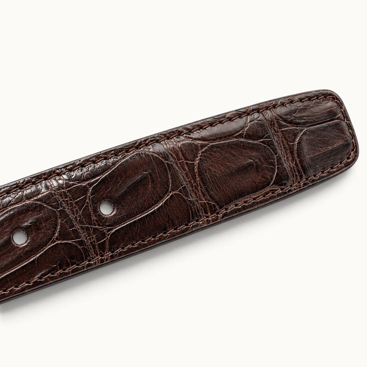 Close-up of The Ellington Crocodile Belt in dark brown, showcasing natural crocodile scales, fine stitching, and belt adjustment holes.