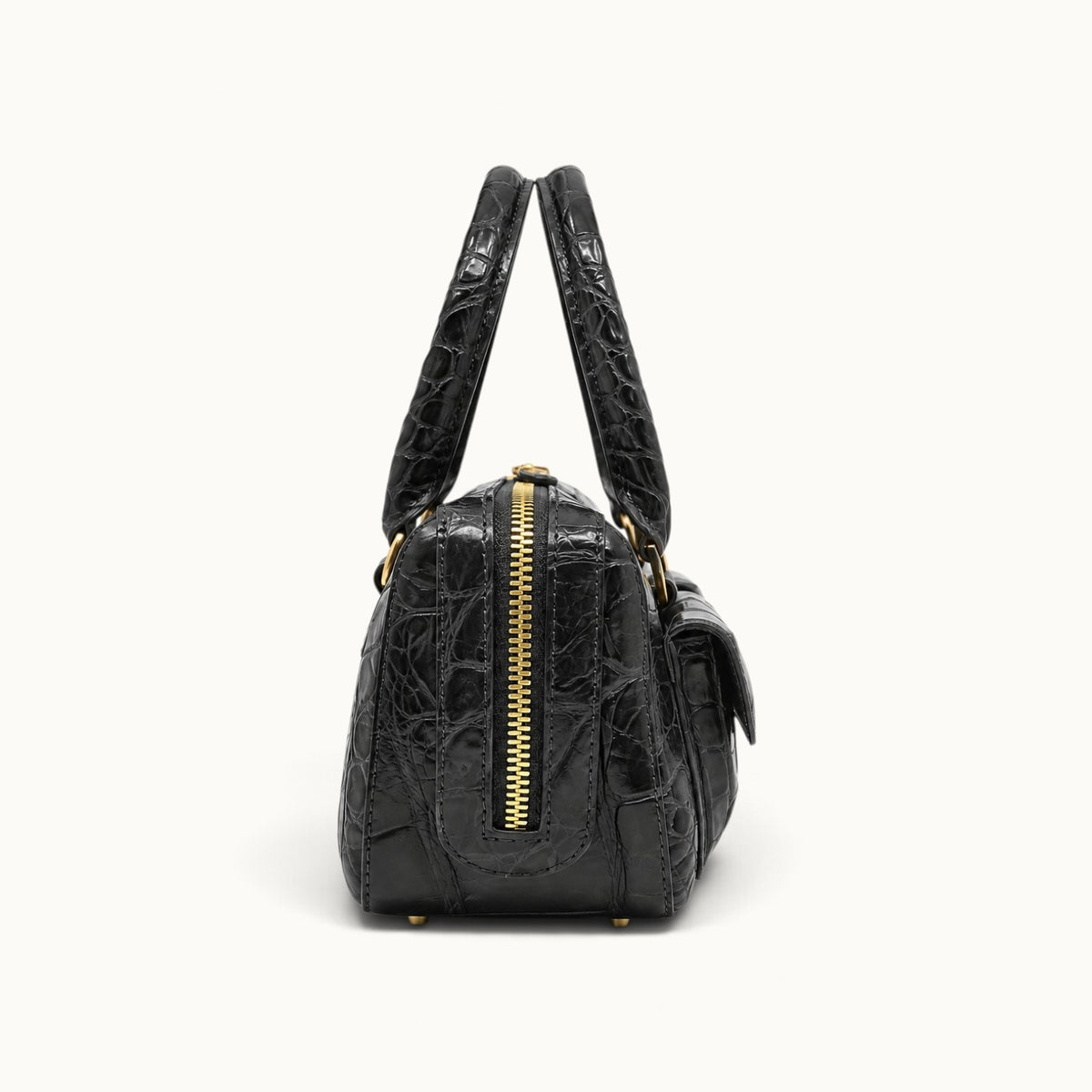 Side profile of The Fairmont Crocodile Handbag in gunmetal showing the structured silhouette, gold-tone zip closure, crocodile leather texture, and top handles.