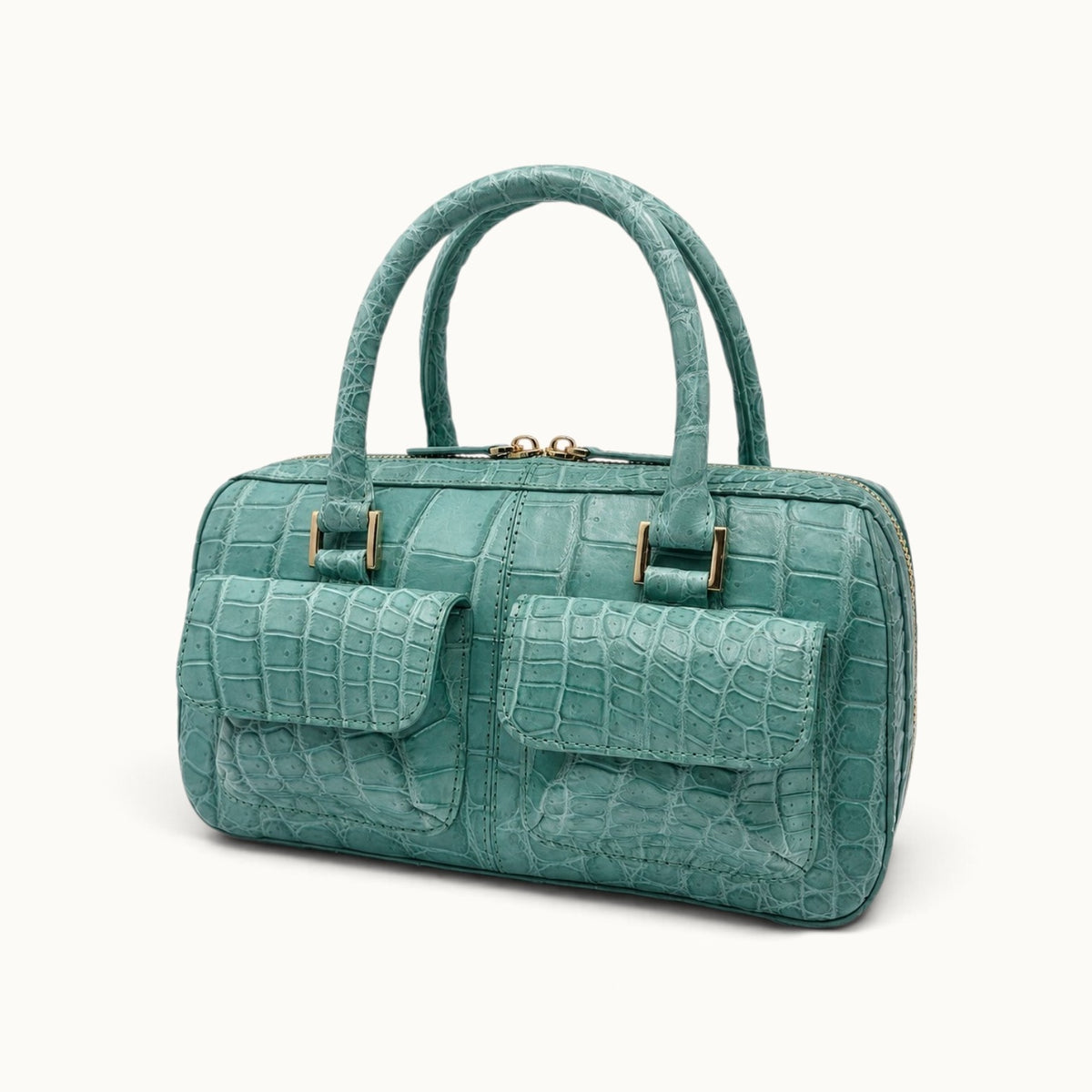 Three-quarter angle view of the Fairmont Seafoam Green Siamese crocodile handbag with two front flap pockets, structured handles, and gold-tone hardware.