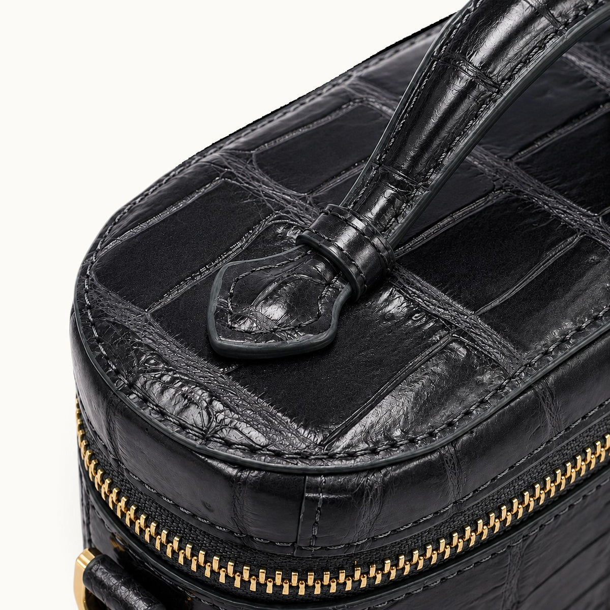 Close-up of Gunmetal Gray crocodile skin with natural scales, gold-tone zipper hardware and detailed handcrafted stitching.