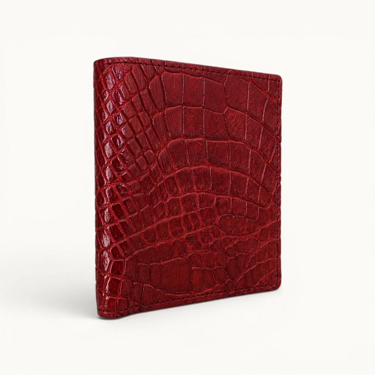 Herrington Cherry Red genuine Siamese crocodile trifold wallet shown from an angled view, highlighting its natural scale pattern, refined stitching, and slim silhouette.